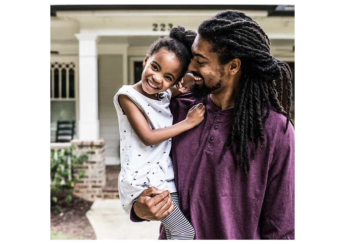 Father and daughter outside their home smiling